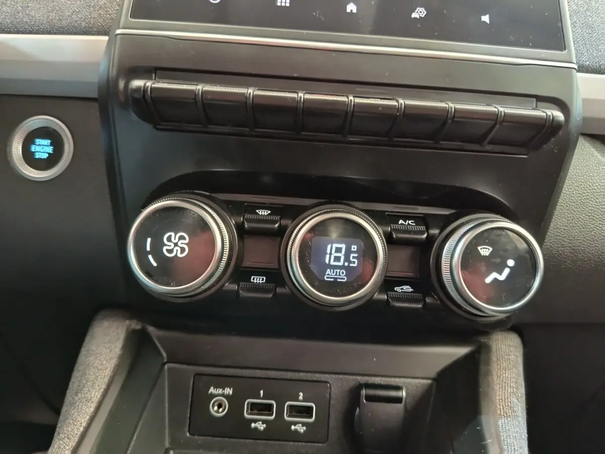 Gros plan sur la console centrale de la Renault ZOE blanche 2021, montrant les commandes de climatisation et le bouton start/stop.