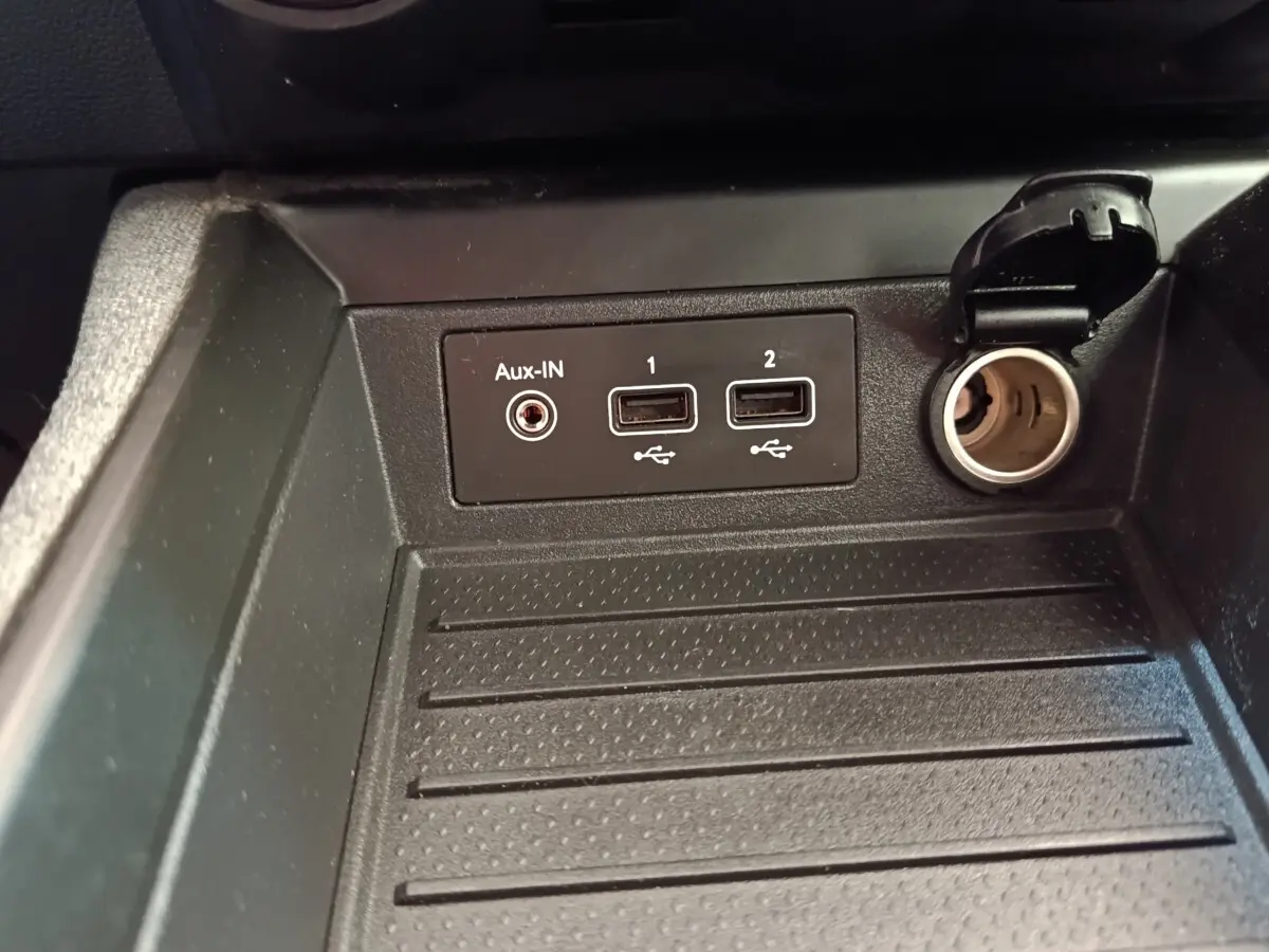 Gros plan sur les prises USB, Aux-IN et prise 12V dans le rangement avant de la Renault ZOE Zen R135 blanche de 2021.