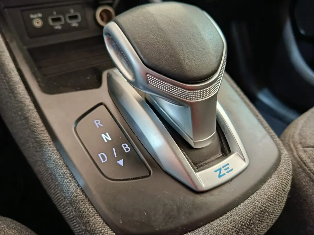 Gros plan sur la commande de boîte automatique de la Renault ZOE blanche, avec logo ZE bleu visible.