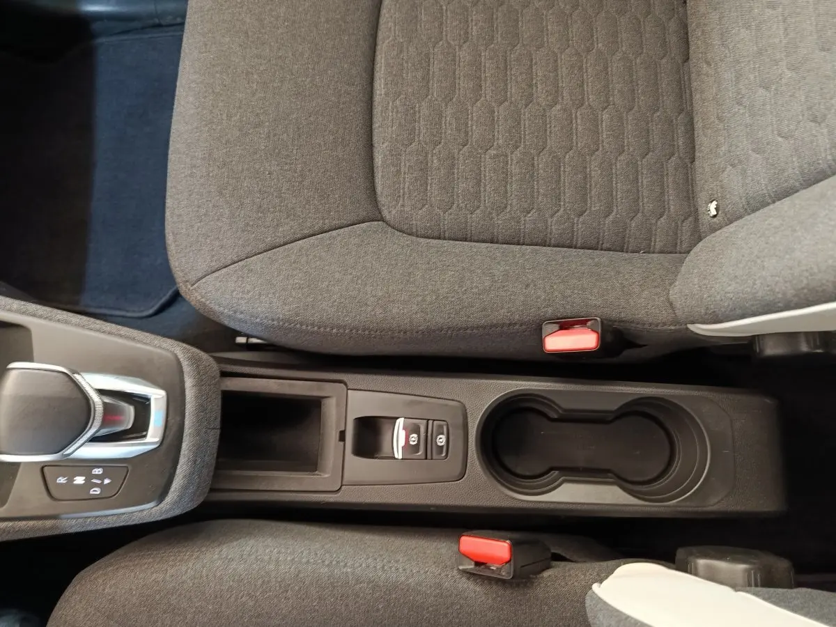 Vue plongeante sur la console centrale et sièges gris de la Renault ZOE Zen R135 blanche, avec levier de vitesse automatique.