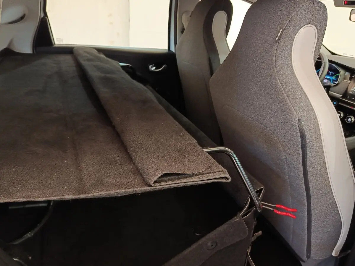 Vue intérieure arrière droite de la Renault ZOE blanche, montrant la banquette rabattue et le coffre partiellement couvert.