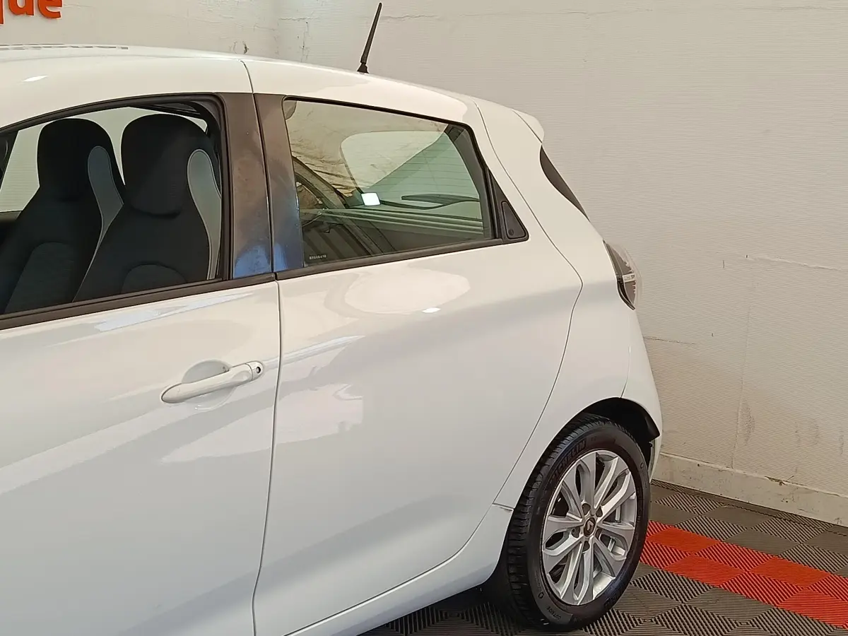 Vue latérale côté gauche d'une Renault ZOE blanche 2021, avec jantes alliage et vitres teintées.