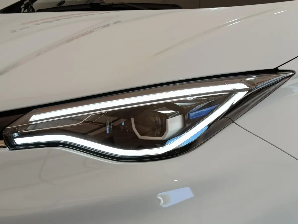 Gros plan sur le phare avant droit LED d'une Renault ZOE Zen R135 blanche, soulignant sa signature lumineuse moderne.