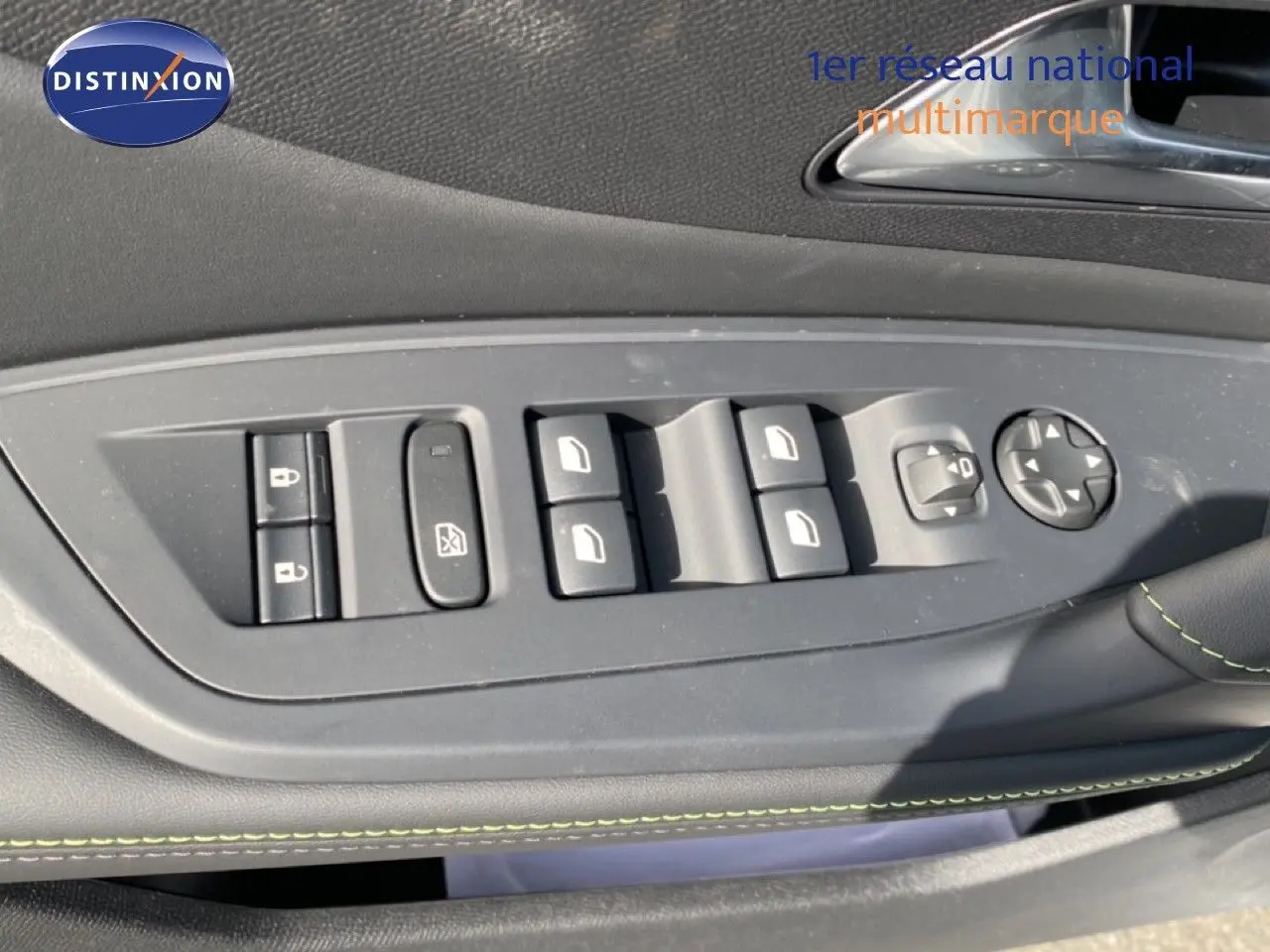 Gros plan sur les commandes des vitres et rétroviseurs côté conducteur d'une Peugeot 308 Hybrid blanche, intérieur noir avec surpiqûres vertes.