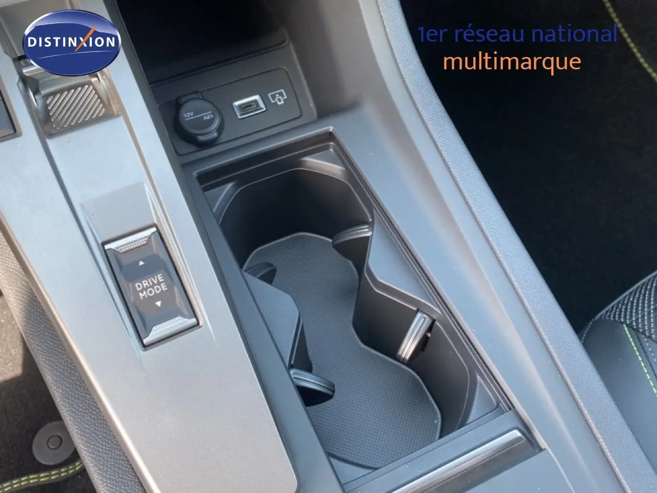 Gros plan sur la console centrale noire de la Peugeot 308 Hybrid 145ch GT, montrant porte-gobelets et bouton Drive Mode.