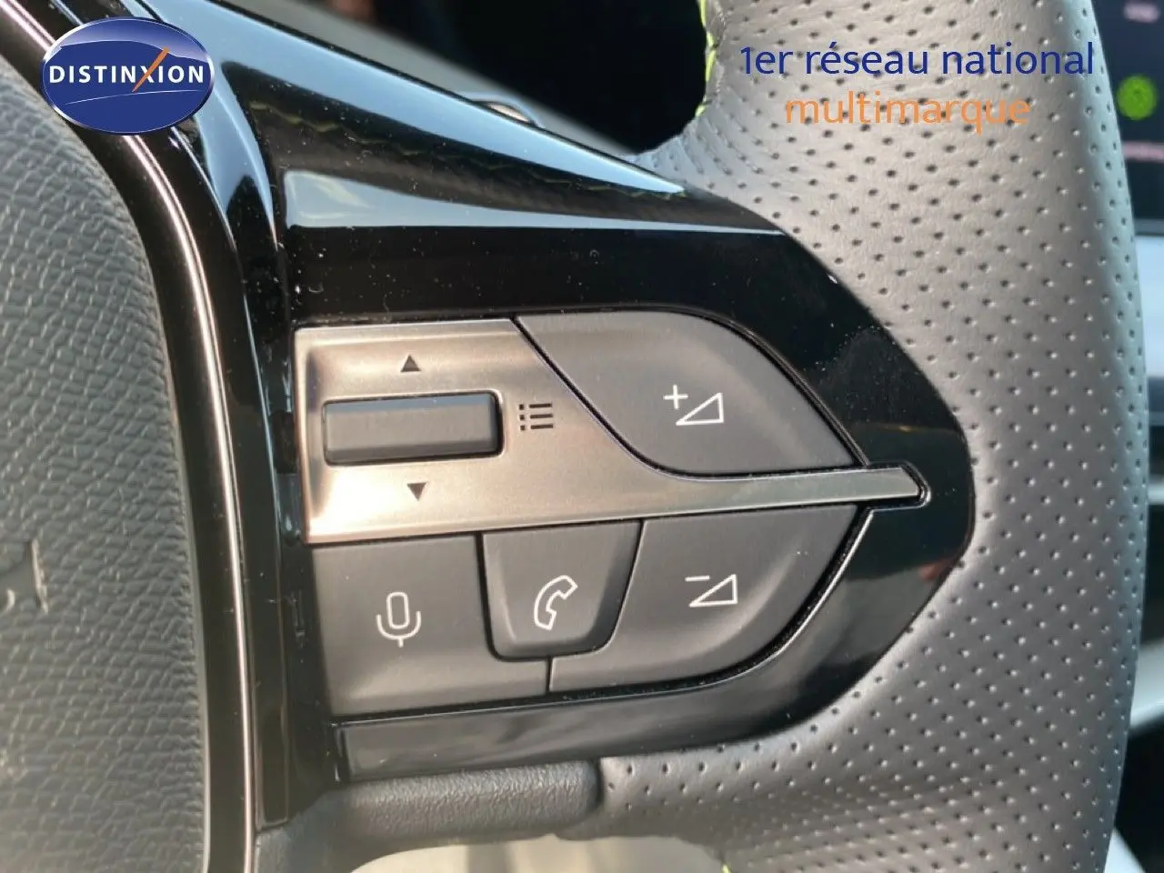 Gros plan sur les commandes noires du volant perforé d’une Peugeot 308 Hybrid 2026, finition GT.