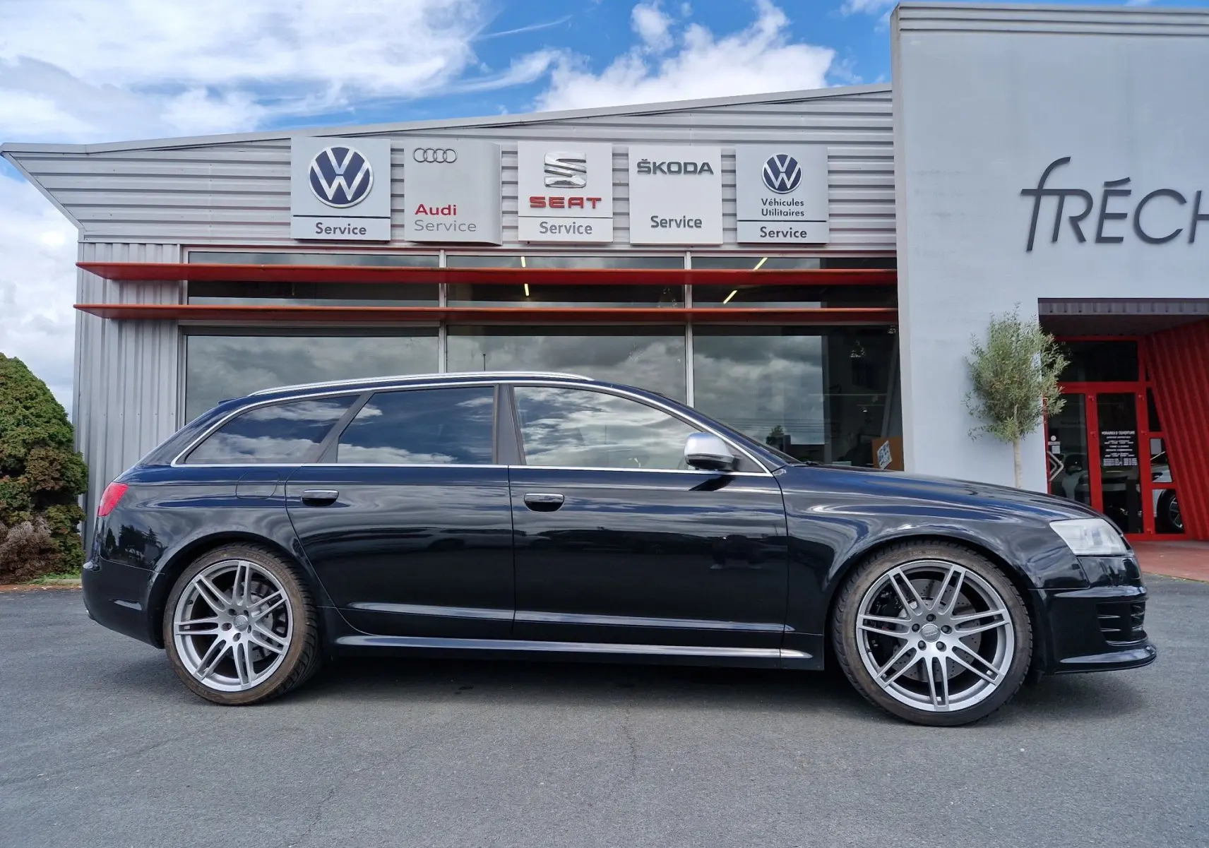 Audi RS6 Avant noir vue de profil côté gauche, soulignant ses jantes alliage sport et son design élégant.