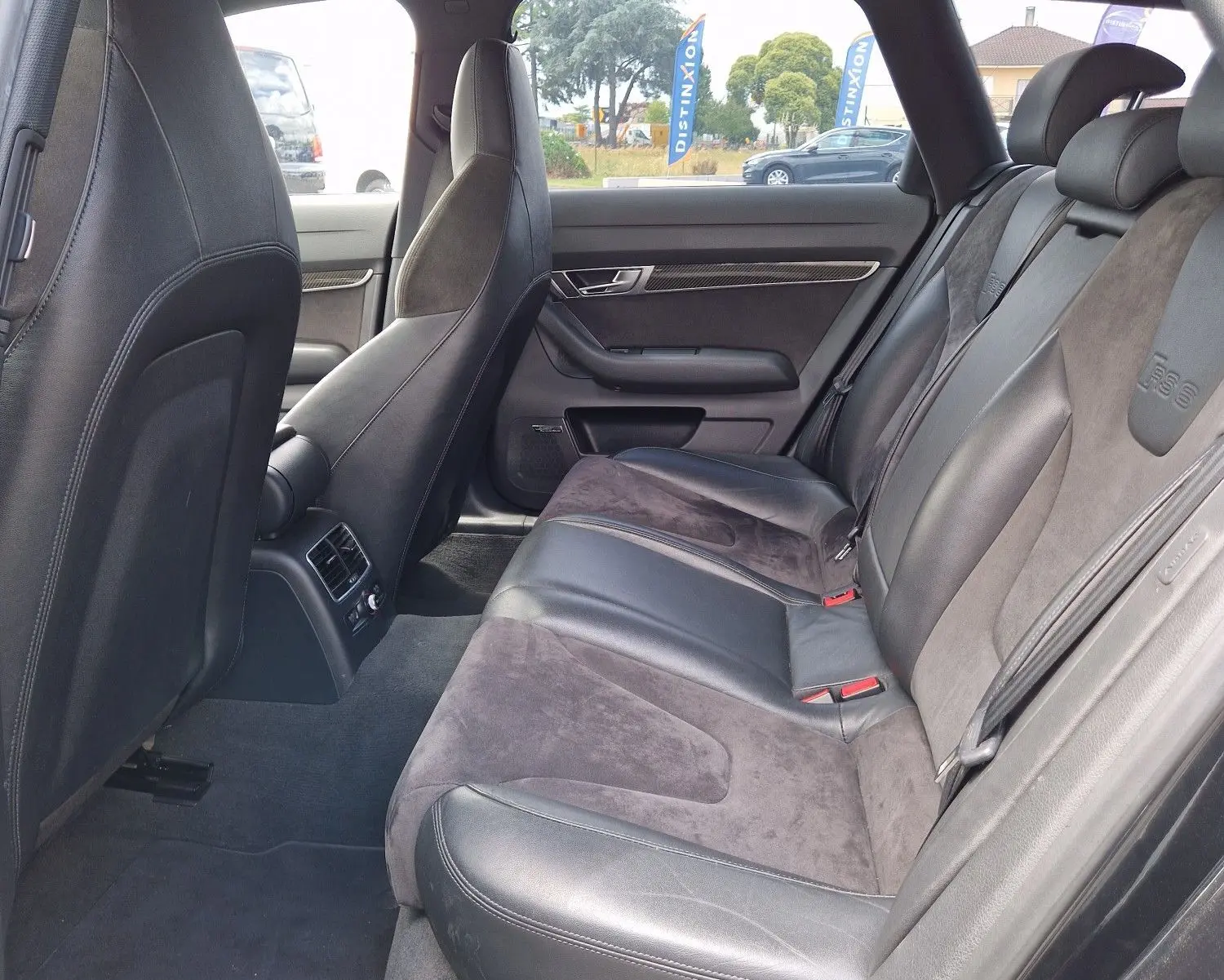 Vue intérieure côté arrière droit de l'Audi RS6 Avant 2009 noire, montrant les sièges en cuir et alcantara avec logo RS6 embossé.