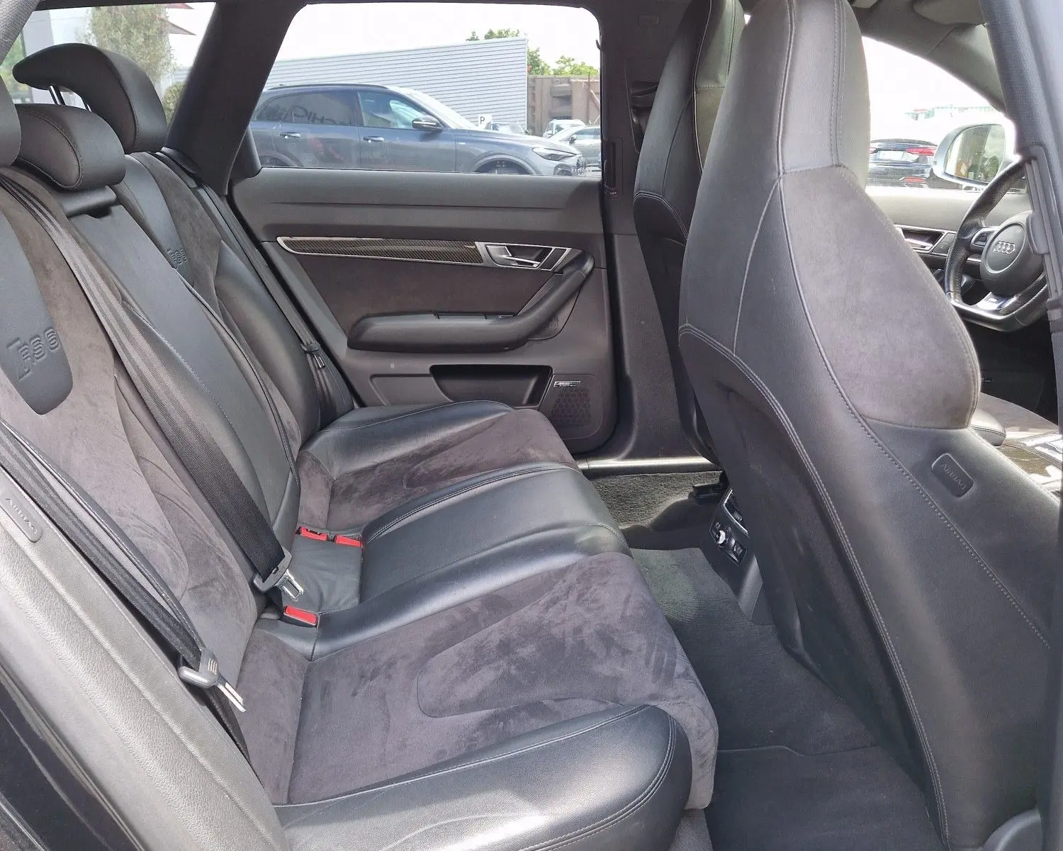 Vue intérieure côté arrière droit de l'Audi RS6 Avant noire de 2009, montrant les sièges en cuir et alcantara avec logo RS6 brodé.