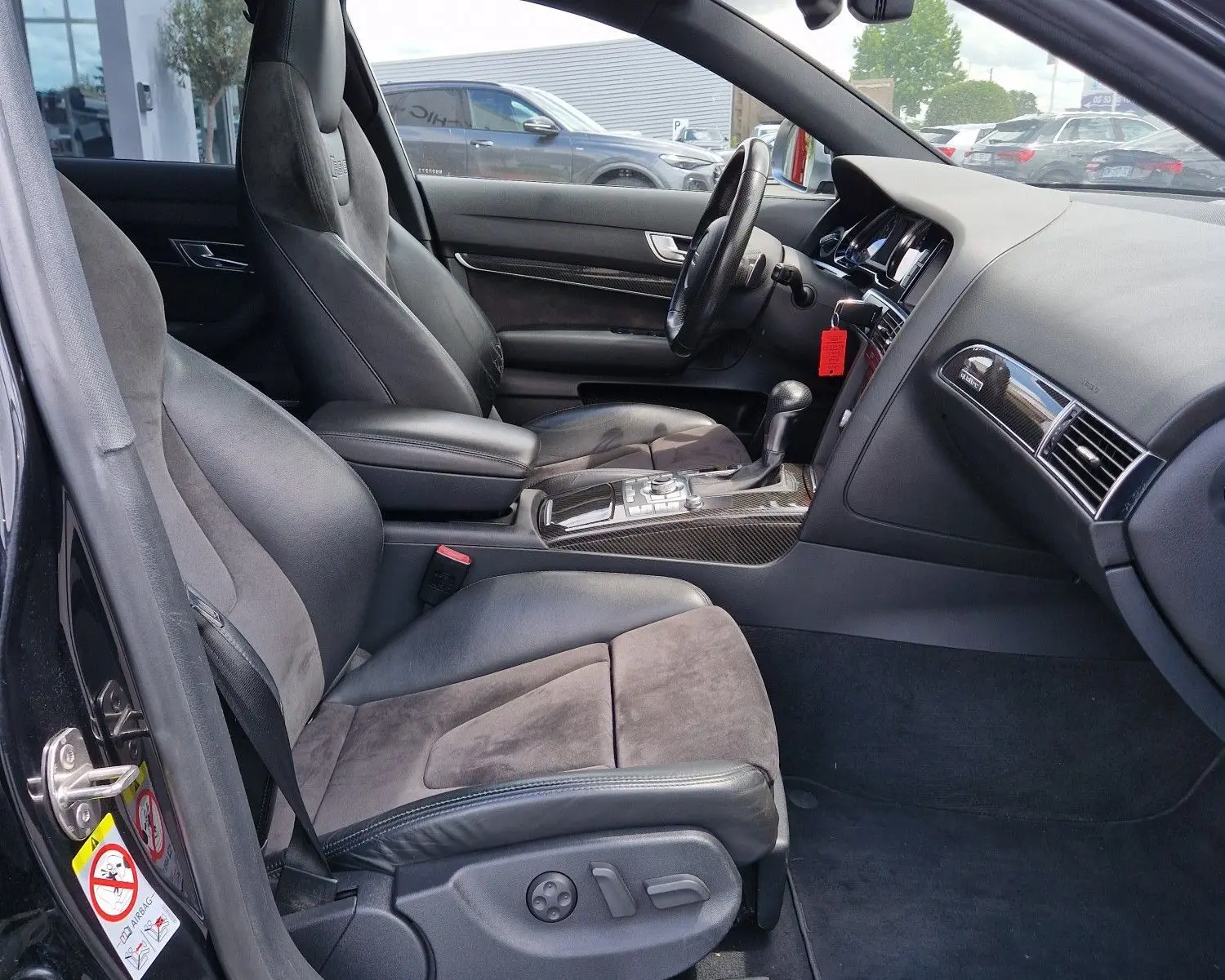Vue intérieure côté conducteur de l'Audi RS6 Avant noire de 2009, avec sièges sport en cuir et alcantara et console centrale en carbone.