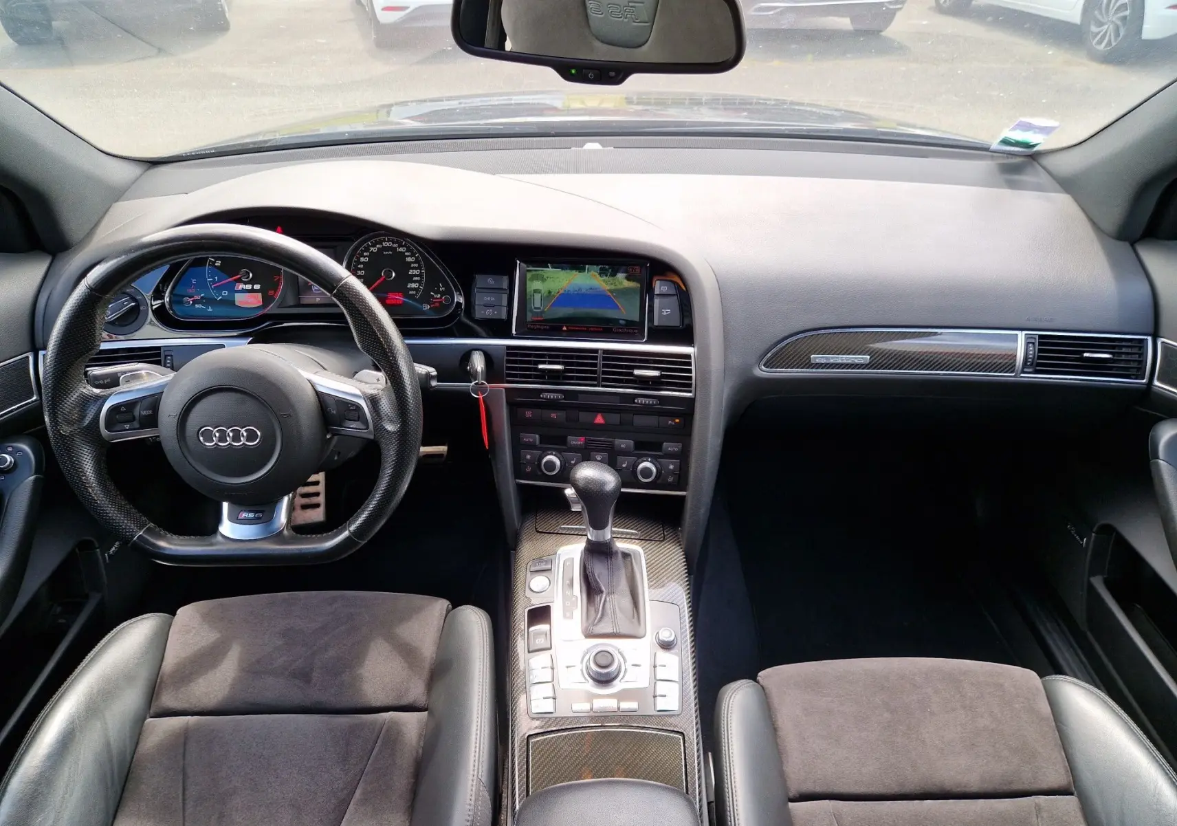 Vue intérieure avant de l'Audi RS6 Avant 2009 noire, avec tableau de bord, volant sport et console centrale en carbone.
