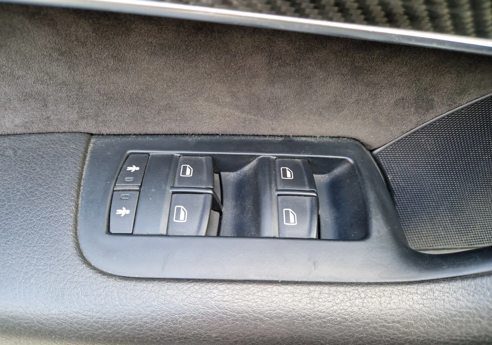 Gros plan sur les commandes de lève-vitres côté gauche de la porte intérieure noire d'une Audi RS6 Avant 2009.