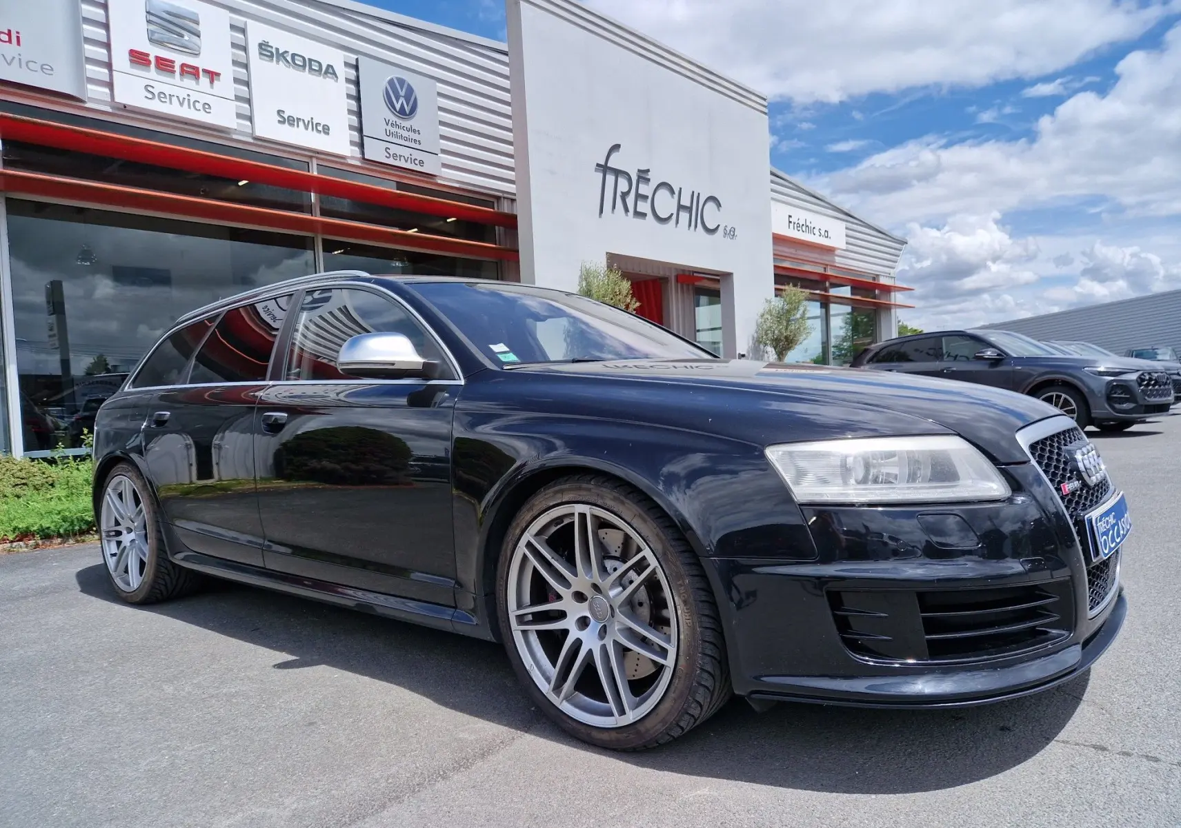 Audi RS6 Avant noire vue en 3/4 avant droit, avec jantes alliage et calandre RS distinctive, stationnée devant un garage.
