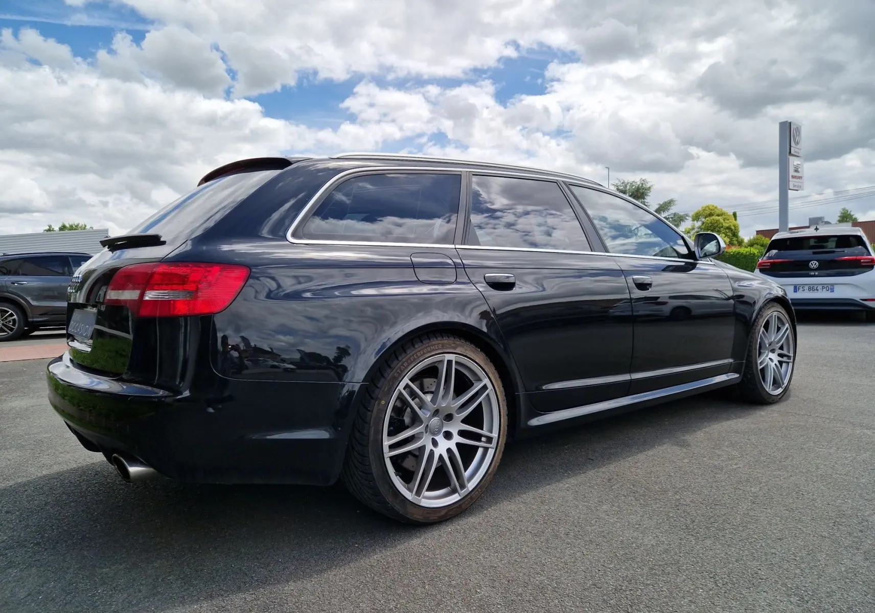 Audi RS6 Avant noir vue 3/4 arrière droit, mettant en valeur ses jantes alliage et ses vitres teintées.