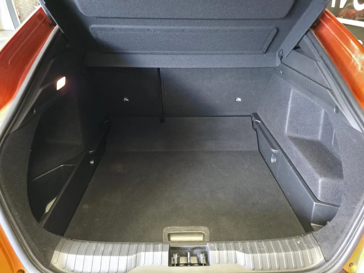Coffre ouvert vu de l'arrière d'un Renault Arkana orange Valencia, montrant un espace de rangement propre et spacieux.