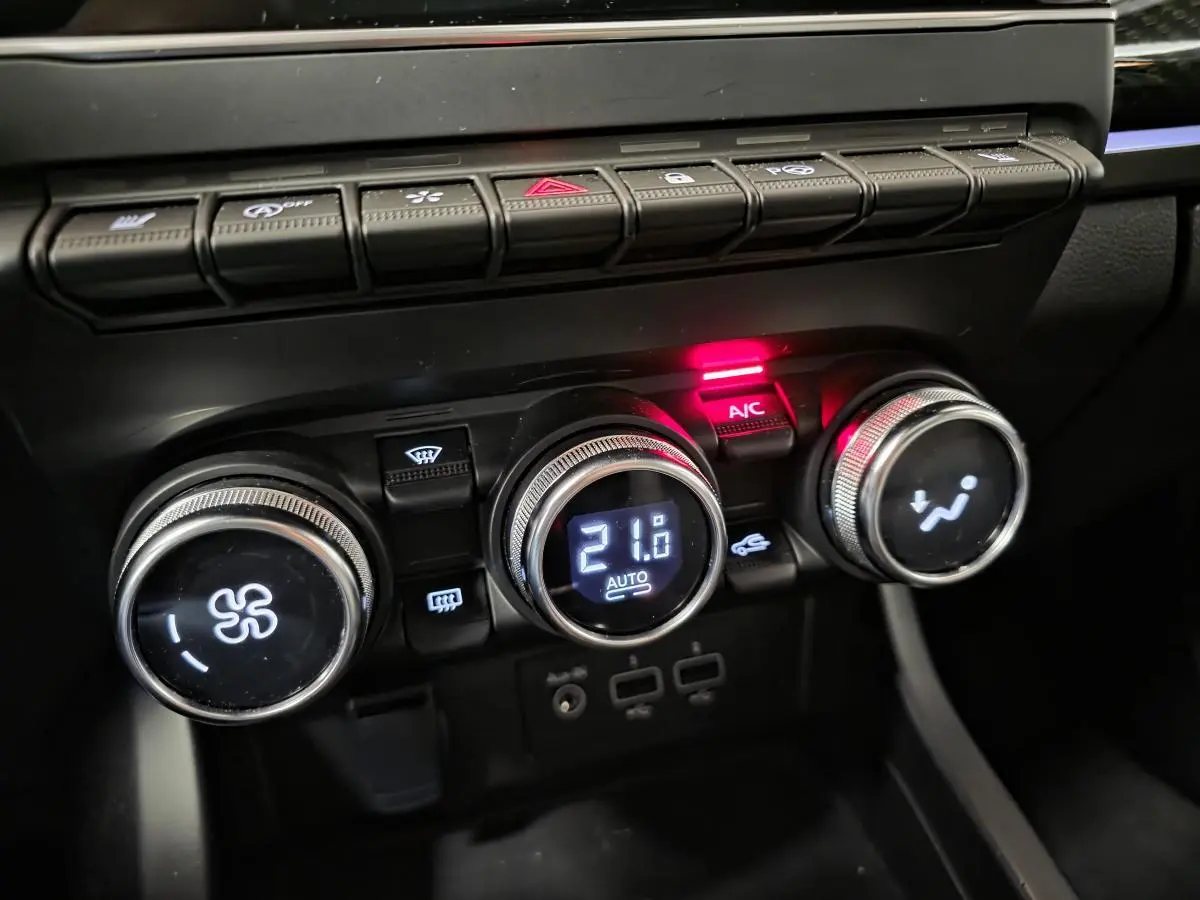Gros plan sur les commandes de climatisation automatique du Renault Arkana 2024 avec affichage digital et boutons rétroéclairés.