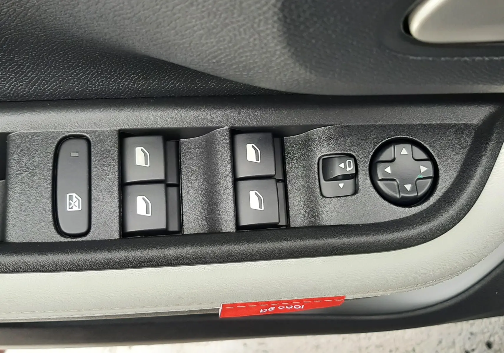 Panneau de commandes des vitres et rétroviseurs sur porte côté conducteur d'une Citroën C3 Aircross gris Mercury avec intérieur gris clair.