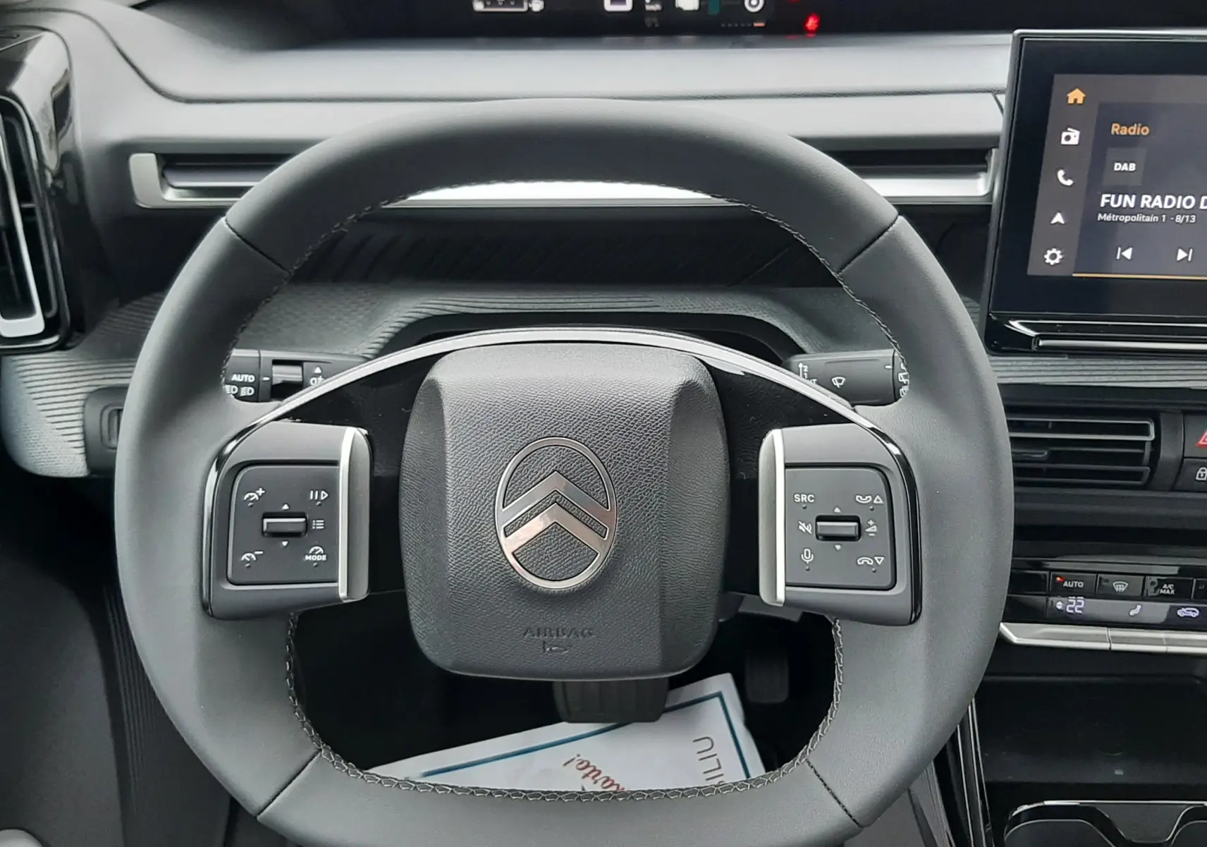 Vue rapprochée du volant noir de la Citroën C3 Aircross 2025, avec tableau de bord numérique et écran tactile visible.