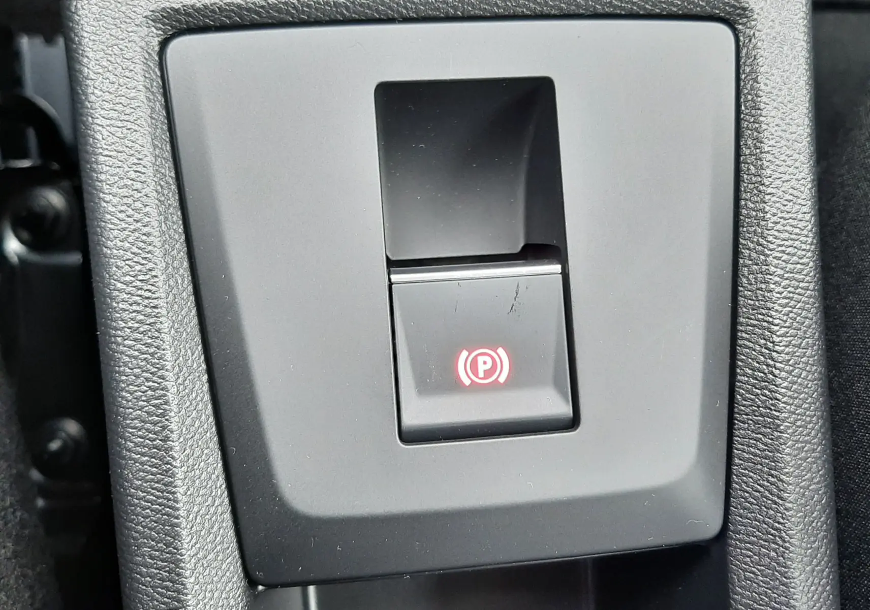Bouton de frein à main électrique allumé sur la console centrale d'une Citroën C3 Aircross gris Mercury toit noir.