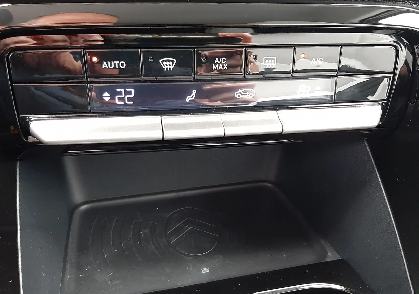 Panneau de commandes climatisation et zone de recharge sans fil noire dans l'habitacle d'une Citroën C3 Aircross 2025 gris Mercury.