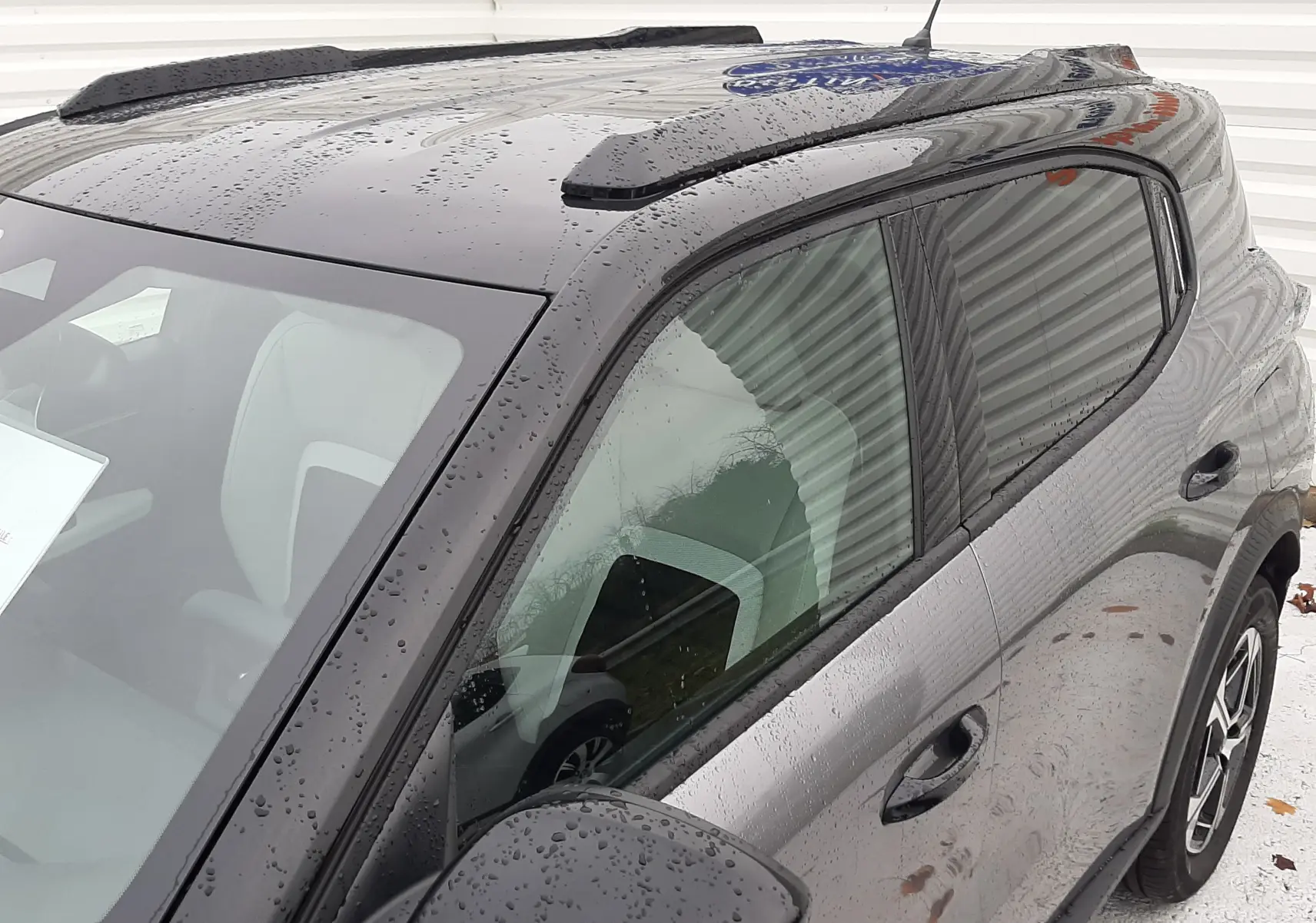 Vue de côté gauche avant du Citroën C3 Aircross gris Mercury avec toit noir et gouttes de pluie visibles.