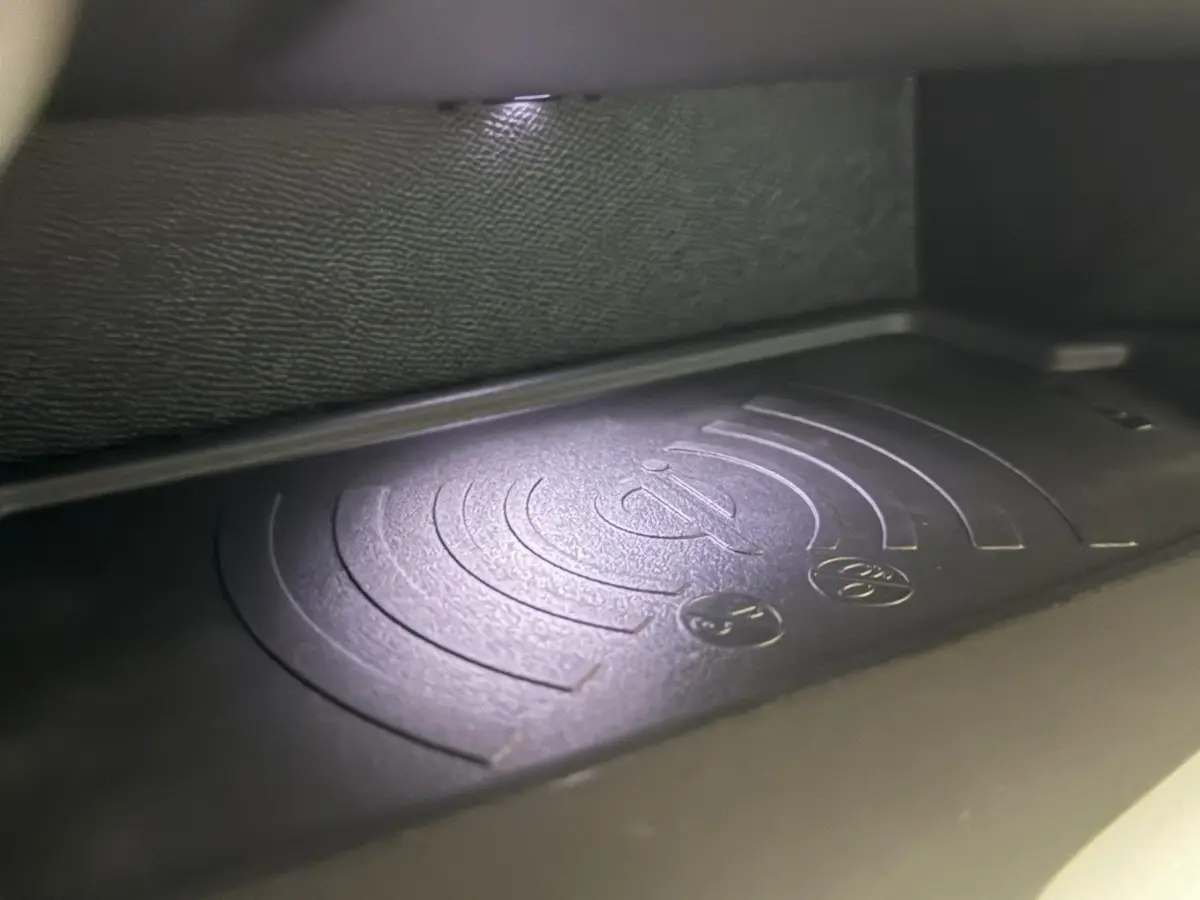 Gros plan sur le chargeur sans fil noir dans l'habitacle de la Peugeot 308 rouge, version BlueHDi 130 AUTO8 ALLURE.