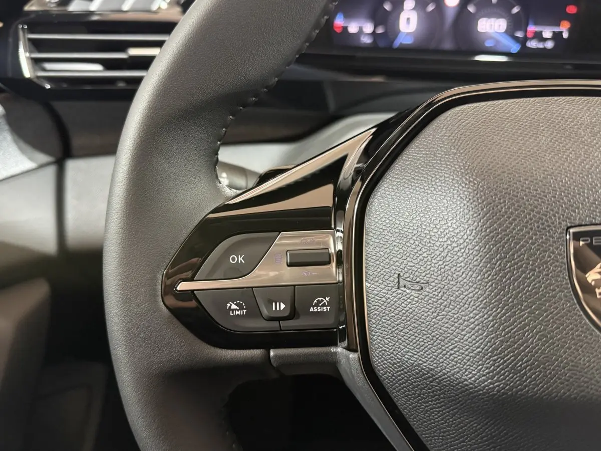 Gros plan sur le volant cuir multifonctions côté gauche du Peugeot 308 2025, avec commandes de régulateur et assistant.