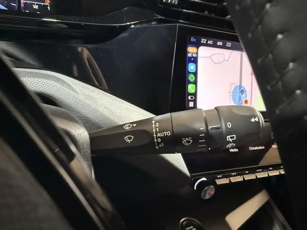 Gros plan sur la commande d’essuie-glace côté gauche du tableau de bord d’une Peugeot 308 2025 avec écran tactile allumé.