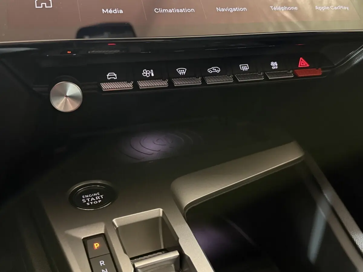 Gros plan sur la console centrale noire de la Peugeot 308 2025 avec boutons tactiles, bouton start/stop et rangement.
