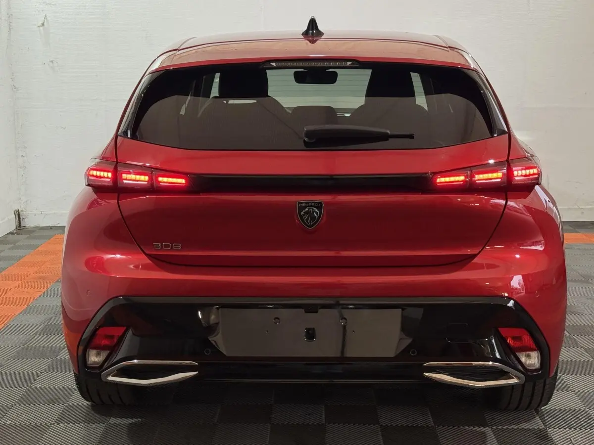 Vue arrière d'une Peugeot 308 rouge 2025 avec feux LED allumés et double sortie d'échappement chromée.