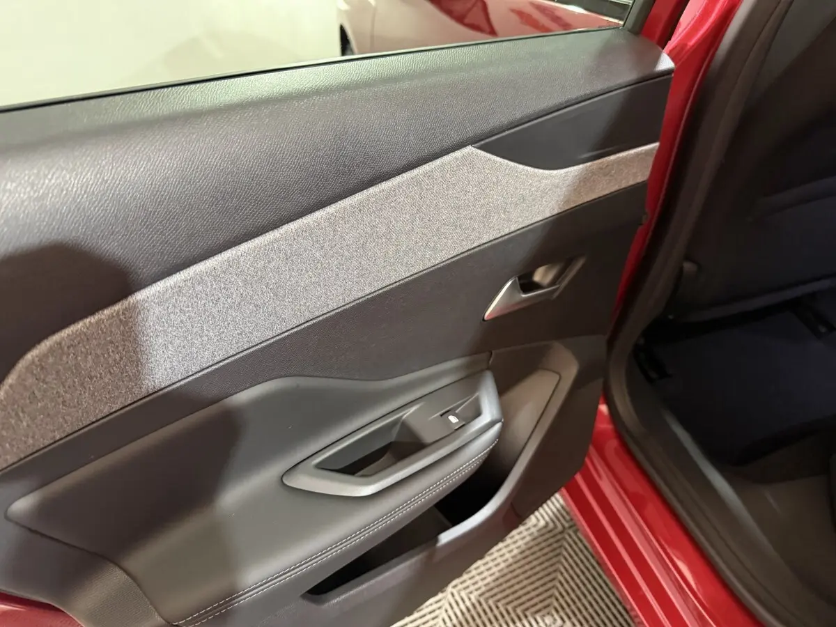 Vue rapprochée de la porte arrière droite rouge d’une Peugeot 308 2025 avec garniture noire et grise.