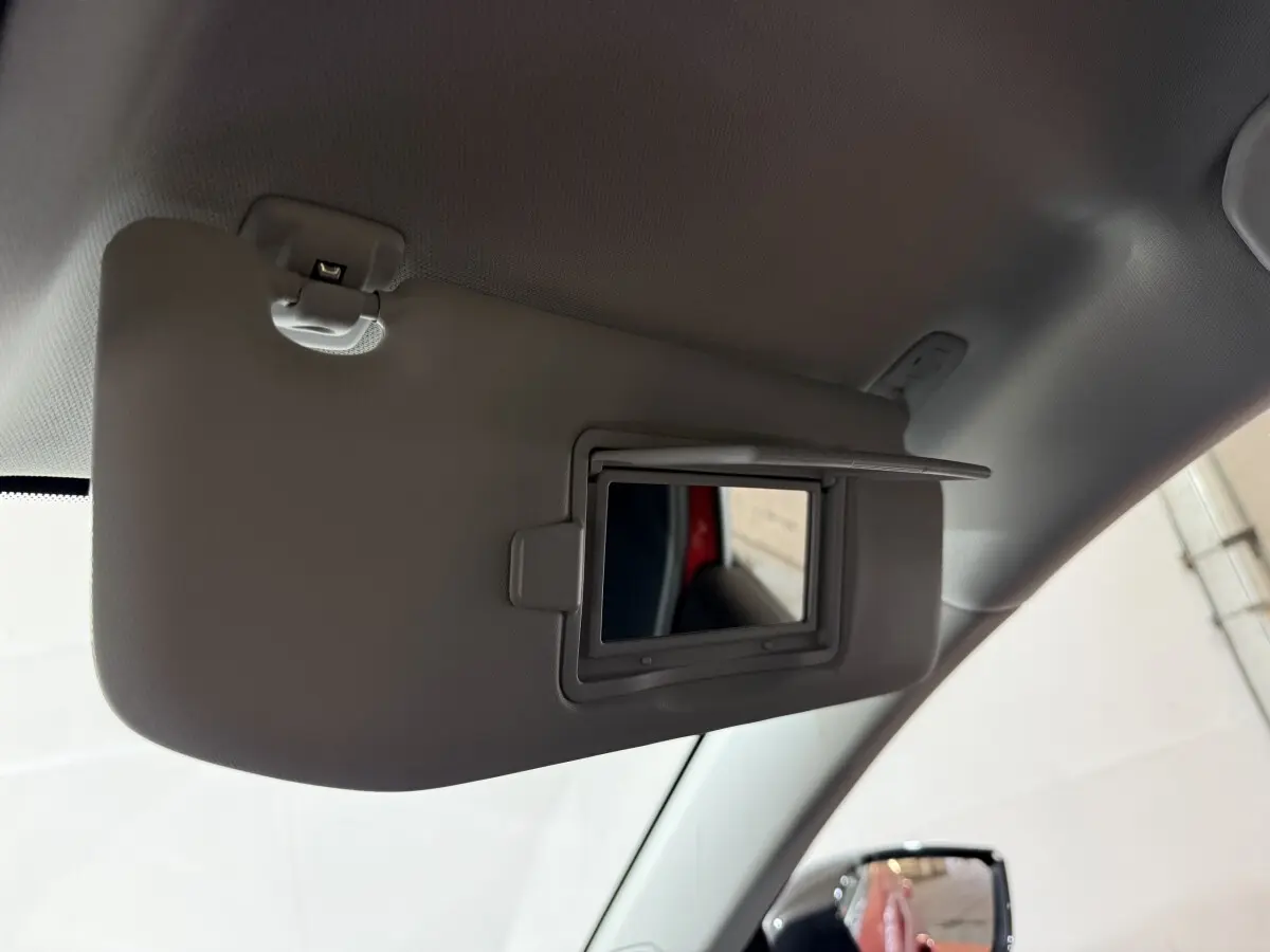 Miroir de courtoisie ouvert sur pare-soleil côté conducteur, intérieur gris, reflet d’une portière rouge Peugeot 308.