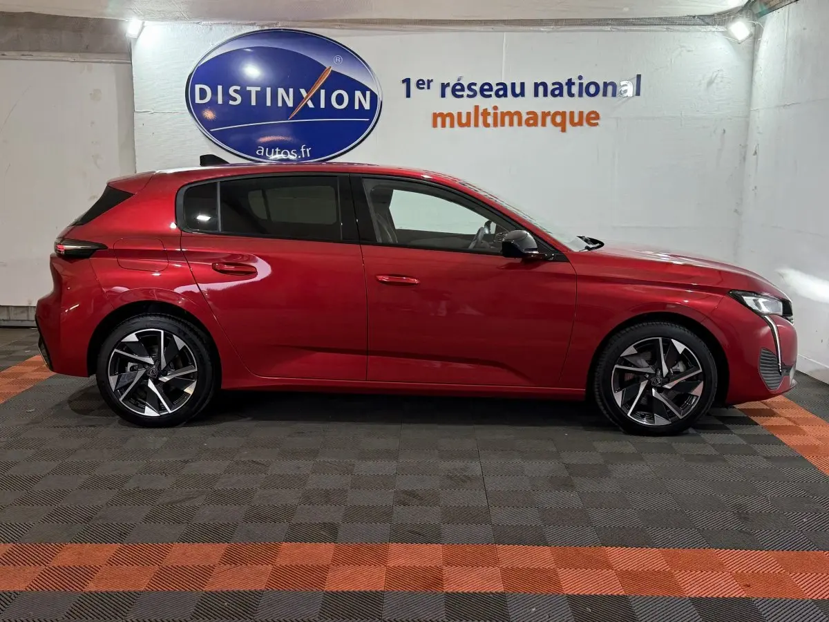 Profil droit d'une Peugeot 308 BlueHDi 130 AUTO8 Allure rouge, stationnée en intérieur avec jantes alliage distinctives.