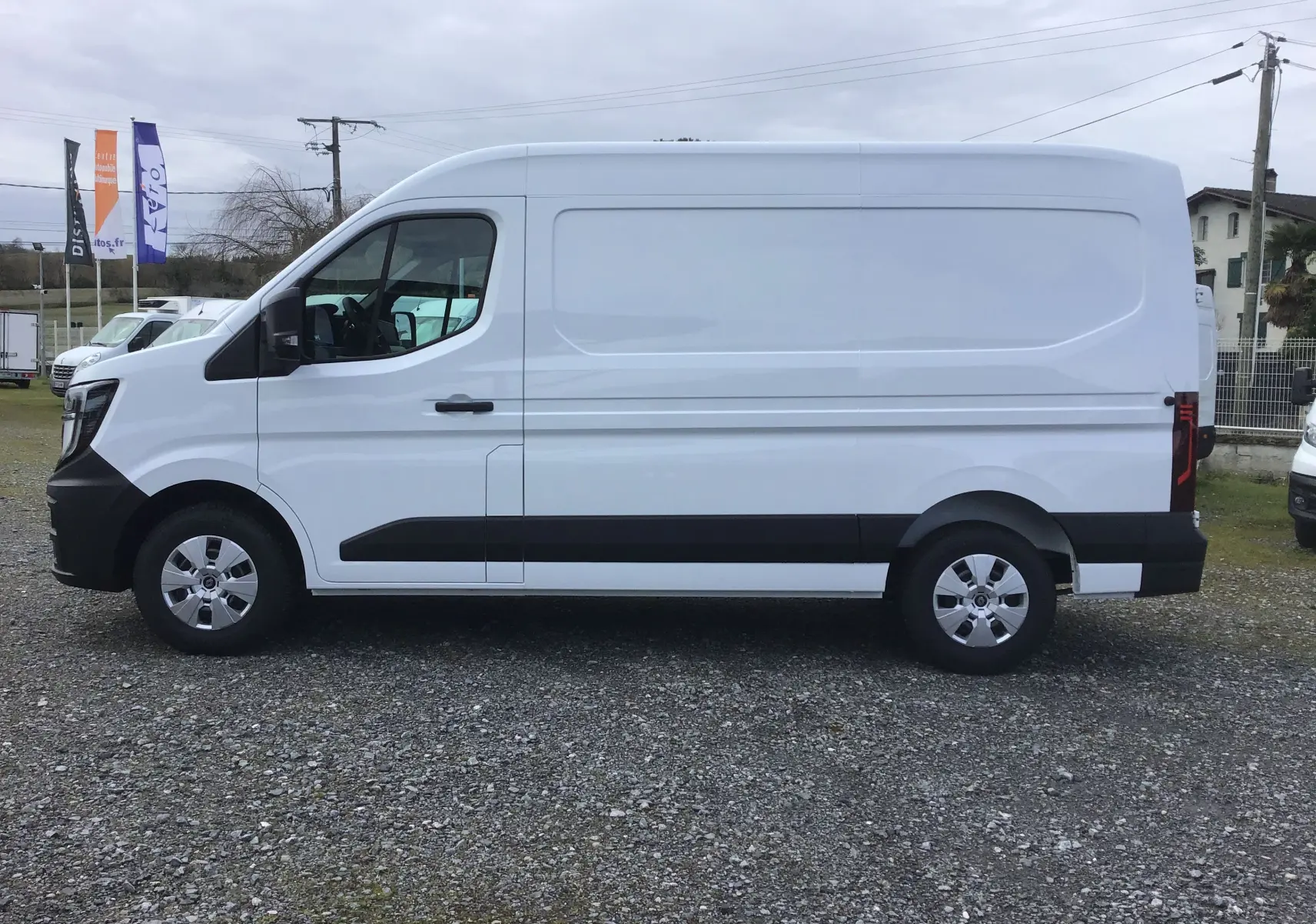 Vue de profil côté gauche d’un Renault Master blanc, fourgon utilitaire avec protections noires sur les bas de caisse.