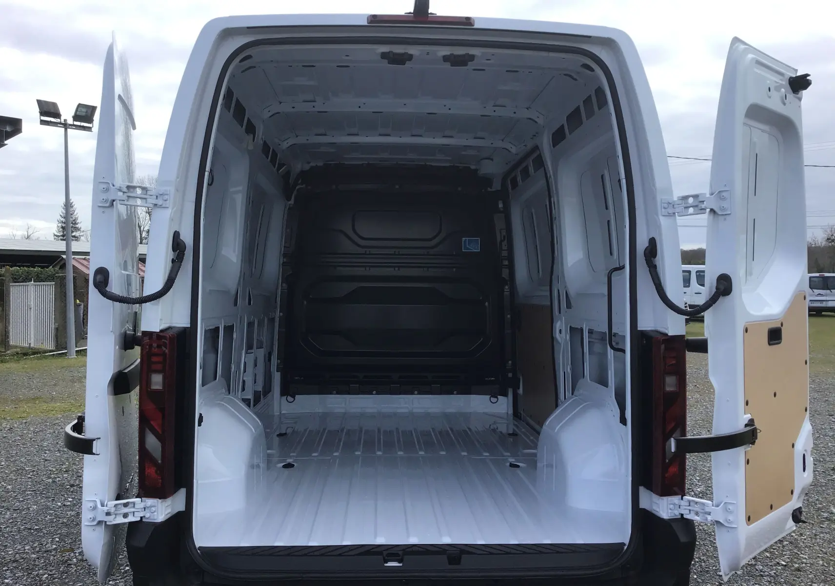 Vue arrière du Renault Master blanc 2025 avec portes ouvertes montrant l’espace de chargement vide et les panneaux intérieurs clairs.