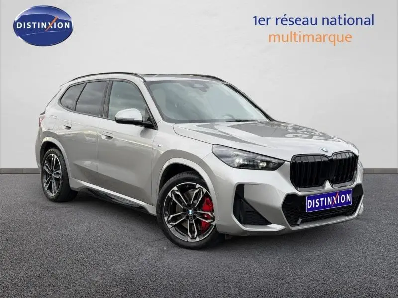BMW X1 xDrive20d M Sport gris Spacesilber métal vue 3/4 avant avec jantes alu et étriers de frein rouges.
