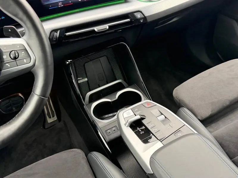 Vue intérieure centrée sur la console centrale et le volant cuir du BMW X1 XDrive20d 2025 en Alcantara noir.