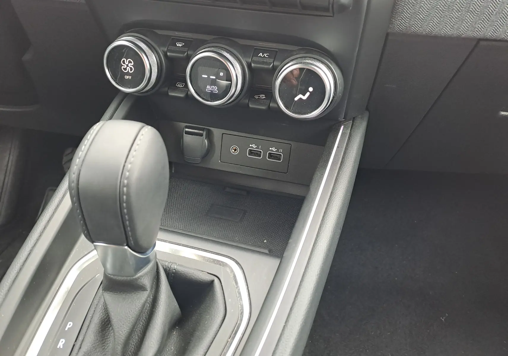 Vue rapprochée de la console centrale de la Renault Clio V 2025, montrant le levier de boîte auto et les commandes de climatisation.
