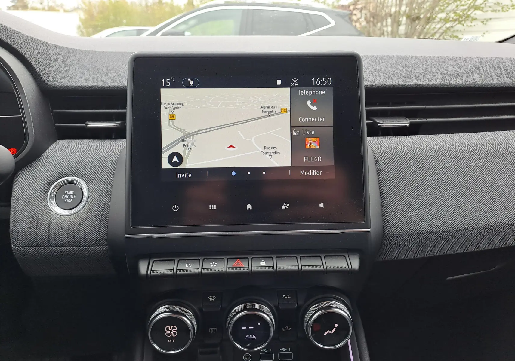 Vue intérieure centrée sur l'écran tactile du tableau de bord de la Renault Clio V, avec volant et partie du pare-brise visibles.