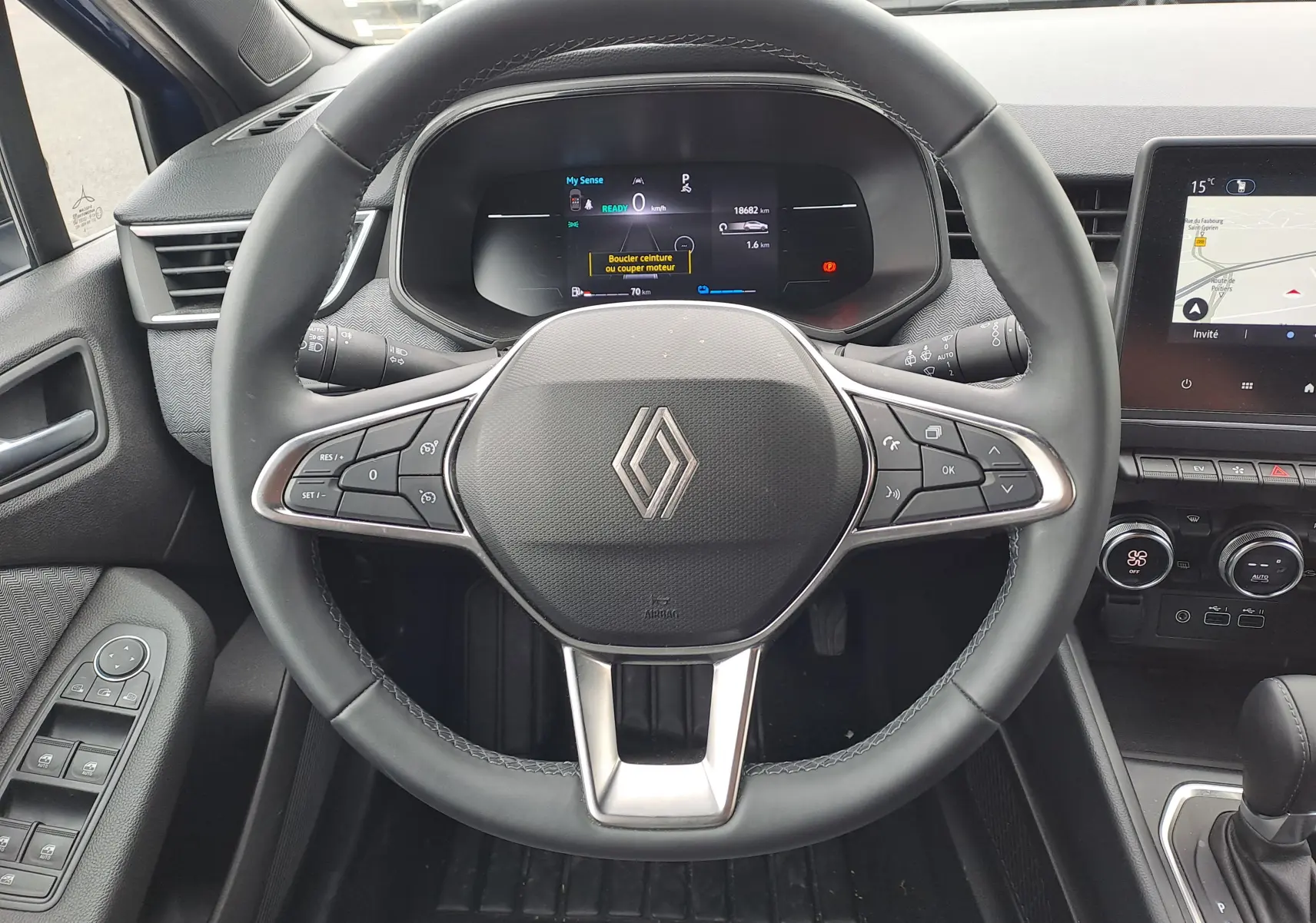 Vue frontale du volant noir de la Renault Clio V avec tableau de bord numérique et écran tactile central visible.