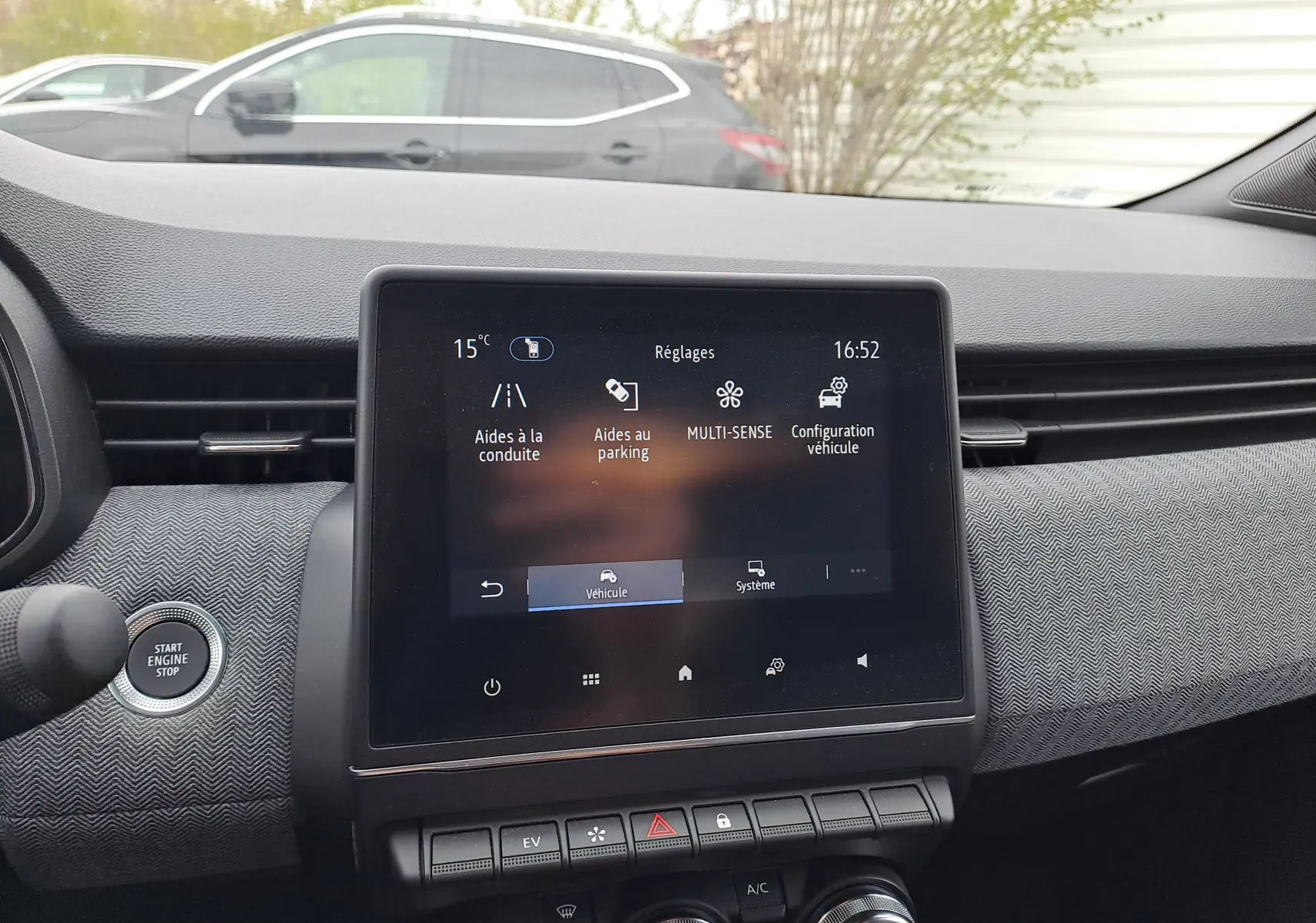 Vue intérieure centrée sur l'écran tactile du tableau de bord de la Renault Clio V bleu Iron Metal, affichant les réglages du véhicule.