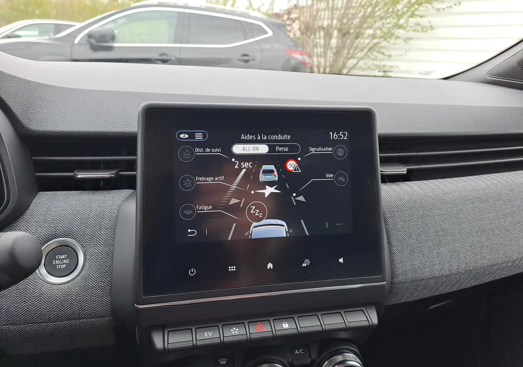 Vue intérieure centrée sur l'écran tactile du tableau de bord de la Renault Clio V bleu iron metal avec commandes visibles.