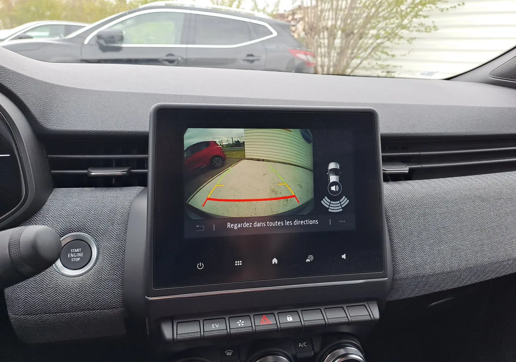 Vue intérieure du tableau de bord de la Renault Clio V bleu iron metal, écran affichant la caméra de recul avec guidage.