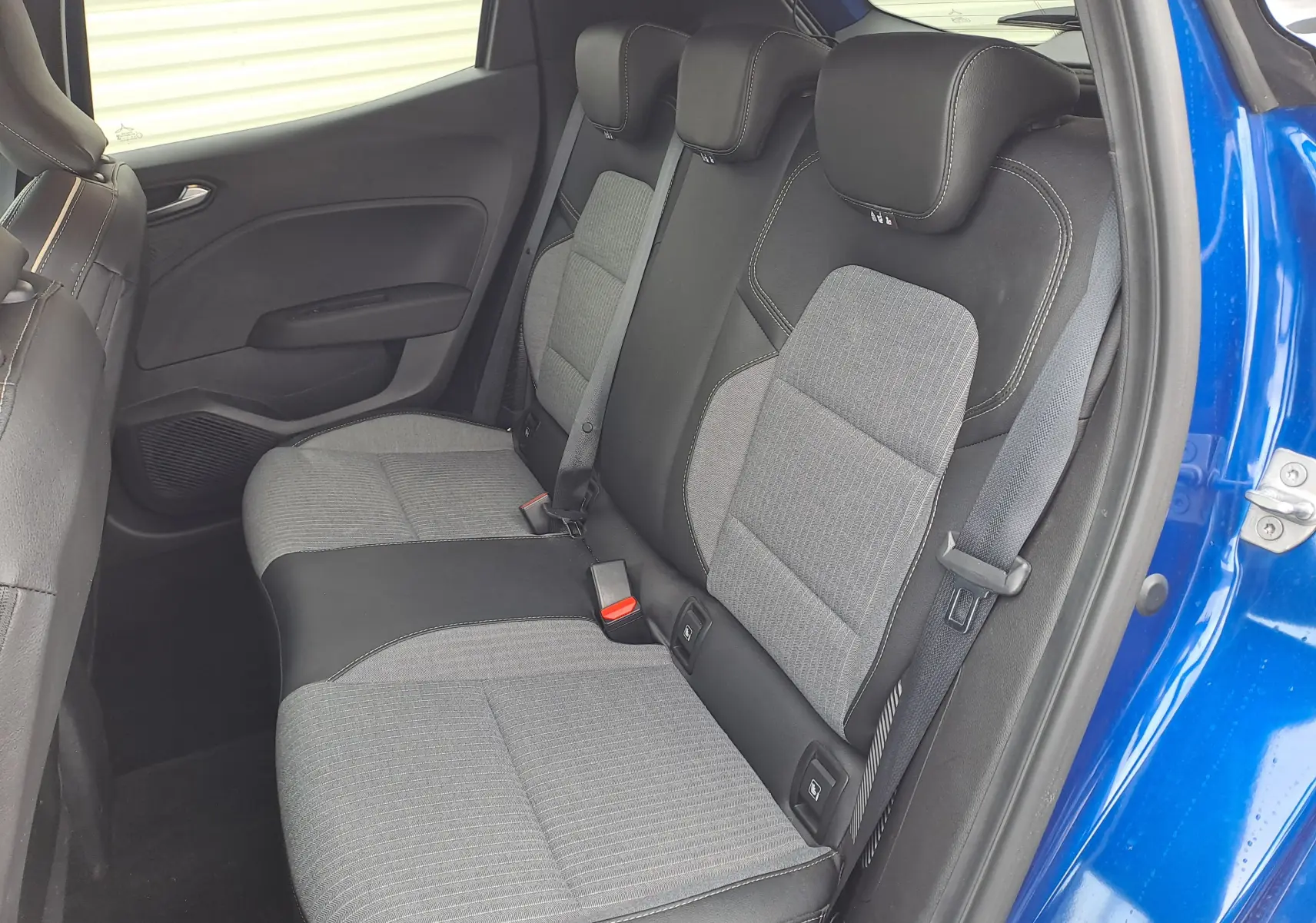 Vue intérieure côté droit des sièges arrière en tissu gris et noir de la Renault Clio V bleu Iron Metal 2025.