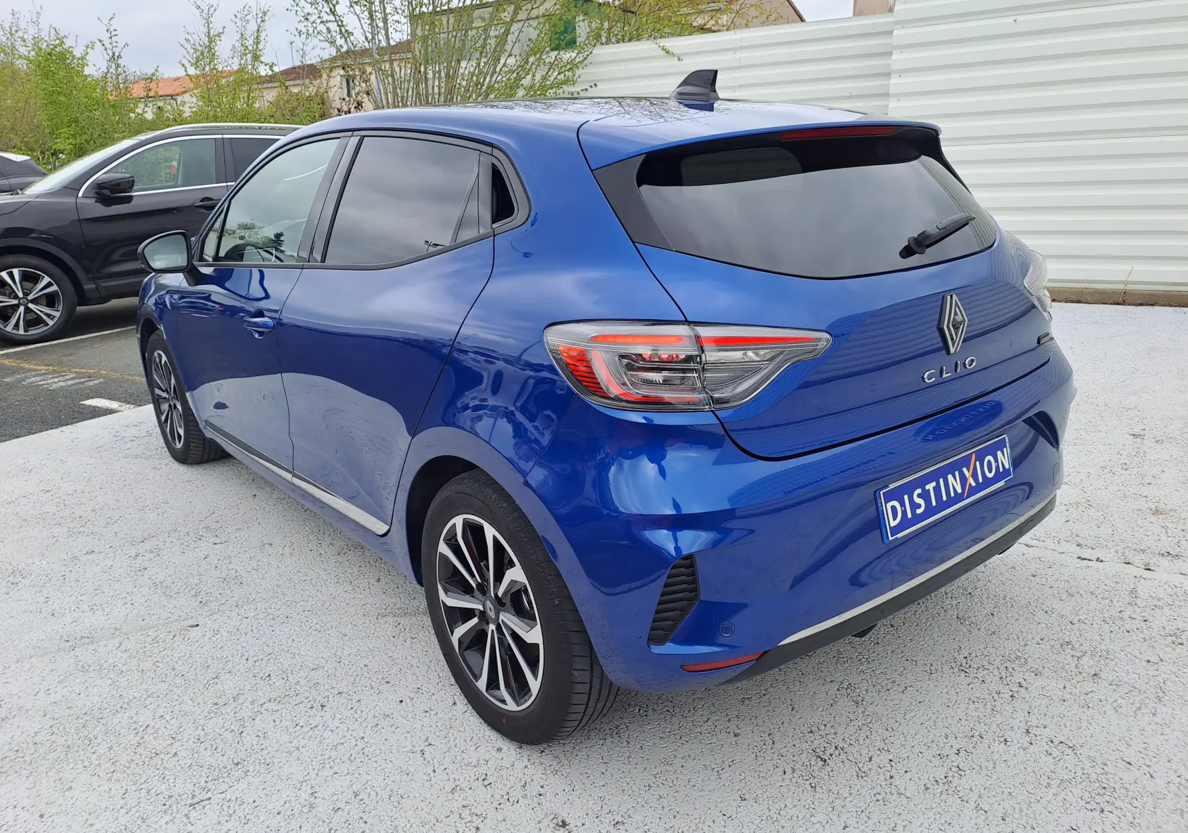 Vue 3/4 arrière droite d'une Renault Clio V bleu iron metal avec vitres teintées et jantes alliage noires.