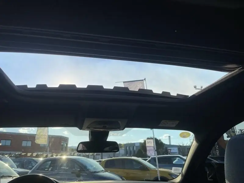 Vue intérieure du toit ouvrant panoramique du BMW X4 30DA X DRIVE noir métal, avec rétroviseur central et ciel dégagé visible.
