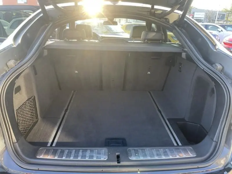 Coffre ouvert vu de l'arrière d'un BMW X4 noir métal 2016, espace de chargement spacieux avec banquette arrière visible.
