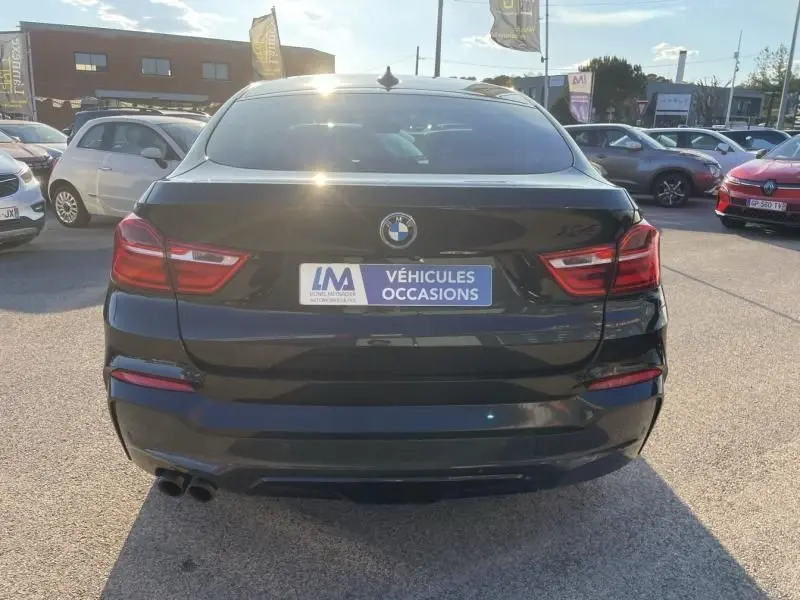 Vue arrière d’un BMW X4 noir métal 2016, avec feux rouges et double sortie d’échappement visible en bas à gauche.