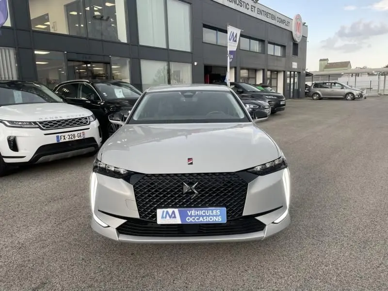 Vue frontale d'une DS4 gris clair hybride rechargeable 2023 avec calandre noire et feux LED verticaux allumés.