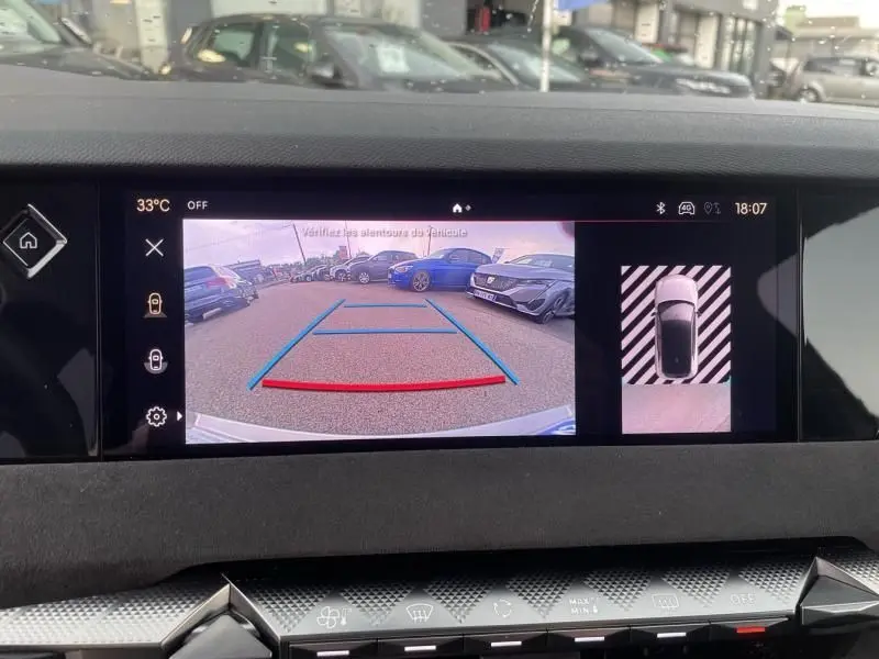Vue de la caméra de recul du DS4 gris 2023, affichant les lignes d'aide au stationnement et l'environnement arrière du véhicule.